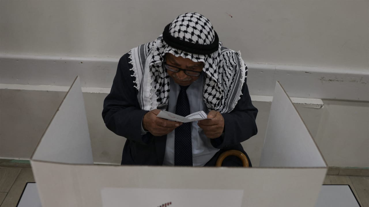 An elderly Palestinian man fills out his ballot before casting his vote at a polling station during municipal elections in the West Bank city of Hebron on April 25, 2026.