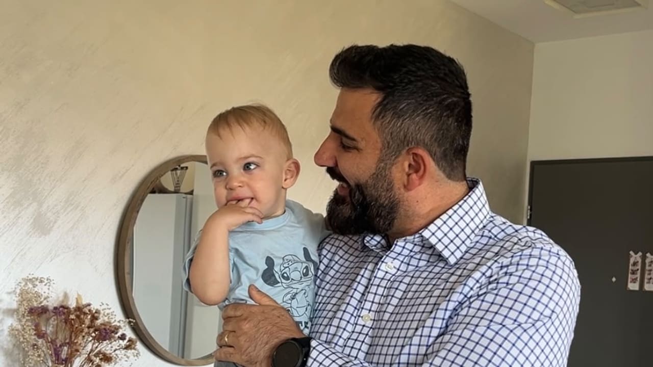 Ramin Parsa holds his child in their family home in Israel
