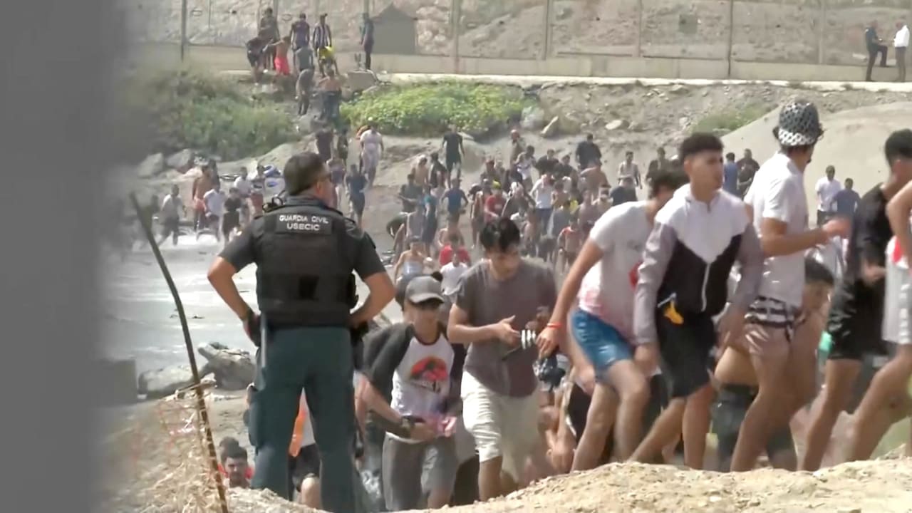 Migrants walk next to a USECIC Guardia Civil member after swimming through Spain's Ceuta border from the Moroccan side to reach the border fence, in Ceuta, Spain, July 30, 2026, in this screen grab obtained from a video