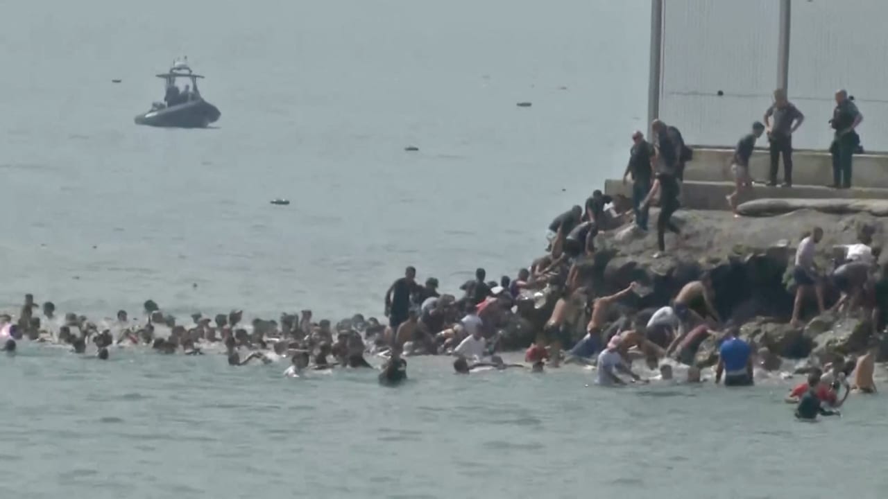 Migrants swim through Spain's Ceuta border from the Moroccan side and climb onto rocks to reach the border fence, in Ceuta, Spain, July 30, 2026, in this screen grab obtained from a video.