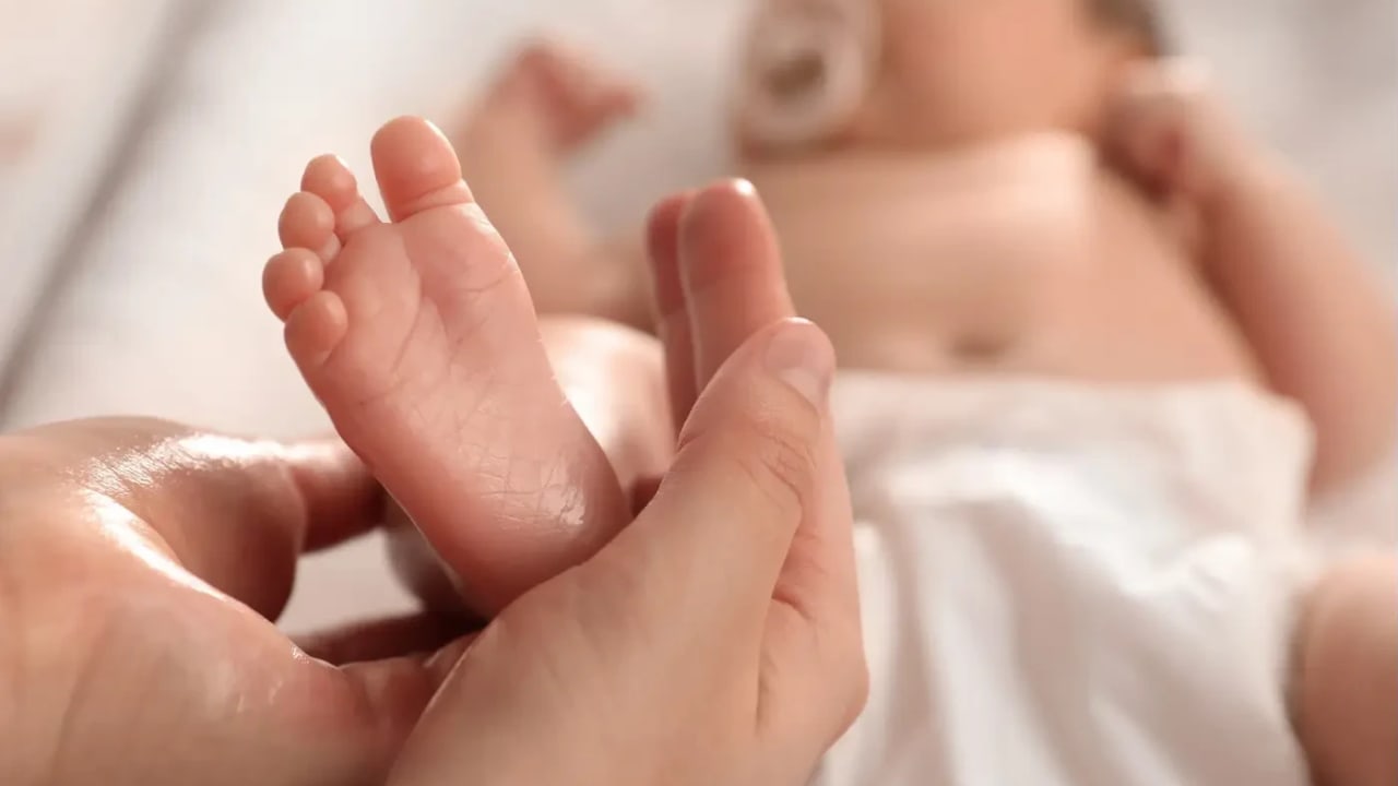 headline: Mother massages her baby’s feet with oil