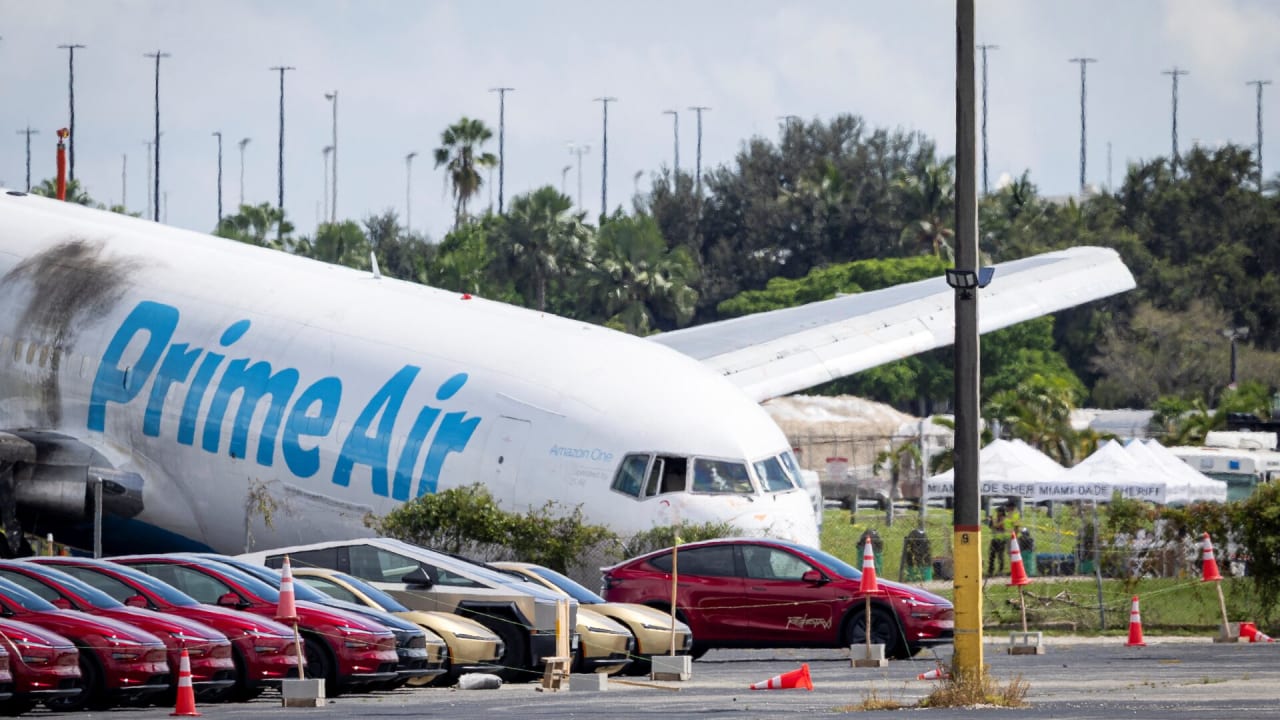 Tesla cars are parked in a lot next to where a crashed Amazon Prime Air cargo plane came to rest, where airport officials said it overran a runway at Miami International Airport, in Miami, Florida, US, September 7, 2026. 