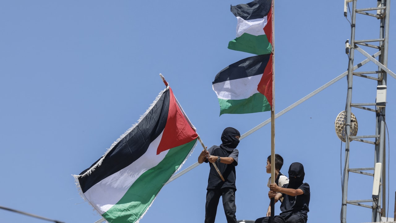  Boys wave Palestinian flags on top of a building in the village of Al-Mughayyir, east of Ramallah in the West Bank, on September 3, 2026.