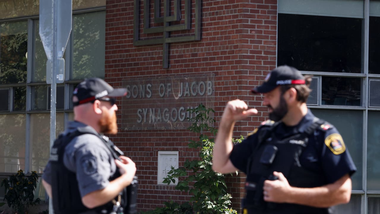 Police officers talk near the scene of a shooting where a police officer was shot outside a Yom Kippur gathering at Sons of Jacob Synagogue in Belleville, Ontario, Canada, September 21, 2026.