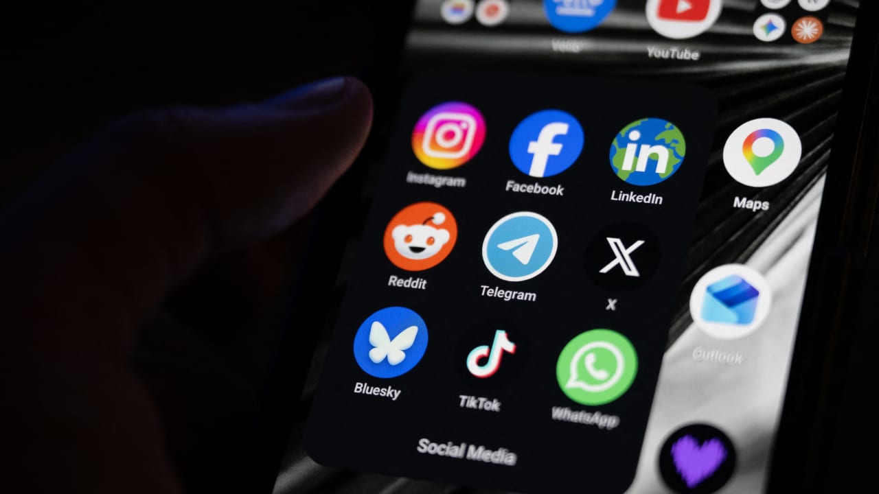 This photograph shows a set up smart-phone screen displaying the logo of main social media platforms including Instagram, Facebook, LinkedIn, Reddit, Telegram, X, Bluesky, Tiktok and Whatsapp.