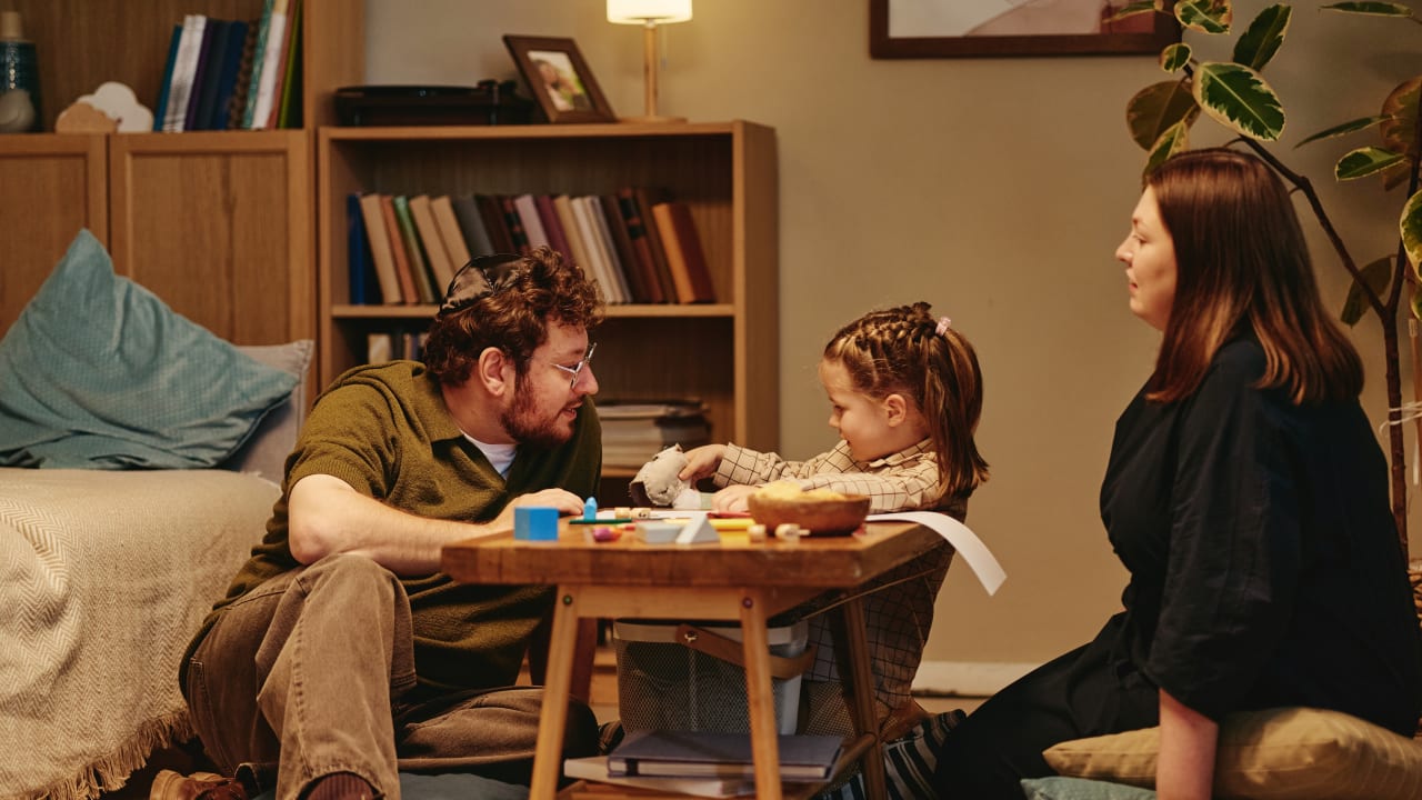 Family sitting on floor playing with girl around coffee table at home