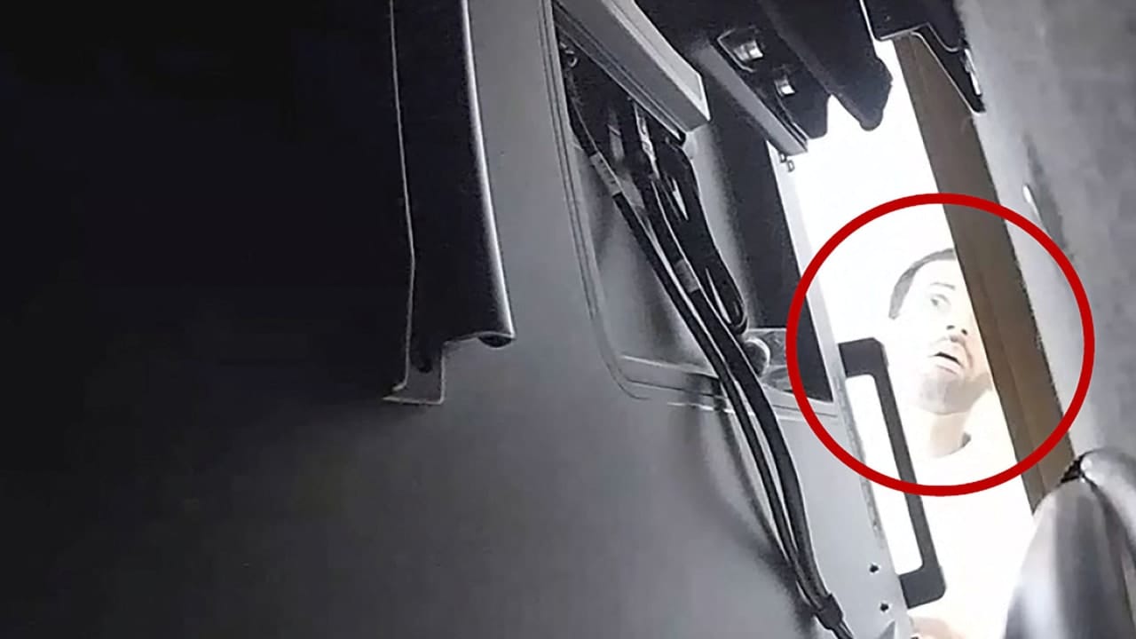 A man described as Abdulrahman Alfozan, a Saudi national employed as an OpenAI engineer, looks behind a television where a recording device had been placed at a conference room in OpenAI offices, in a still image from surveillance video included in a charging document. October 5, 2026.