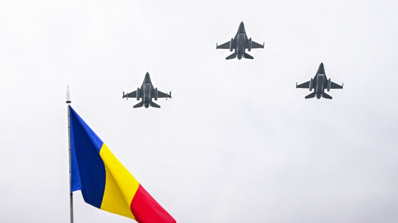 Three F-16 fighting jets of the Romanian Air Force fly over a Romanian flag during a military parade marking the National Day of Romania in Bucharest December 1, 2023.