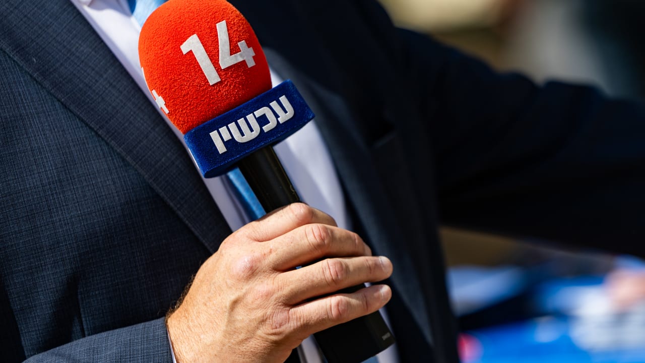  reporter holds a microphone of Israel’s Channel 14 news at a polling station during the Likud primary elections in Jerusalem, August 17, 2026.