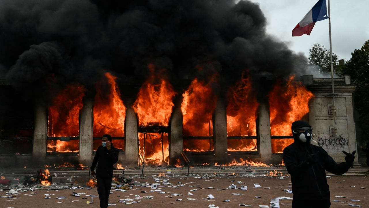 Protesters stand in front of Lyon’s tourism office set on fire during a demonstration to protest against the ‘high cost of living,’ in Lyon last week.