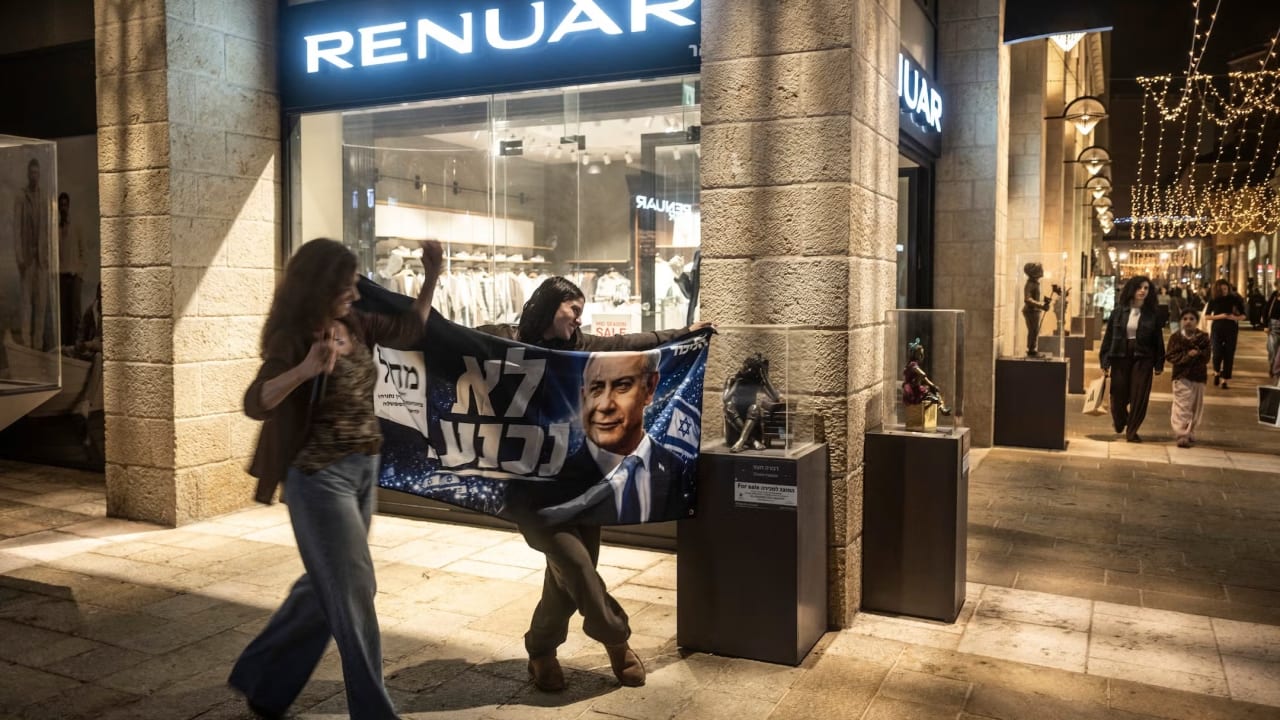 A young supporter of Israeli Prime Minister Benjamin Netanyahu poses with an electoral banner next to a musician in a market area in Jerusalem on October 21, 2026.