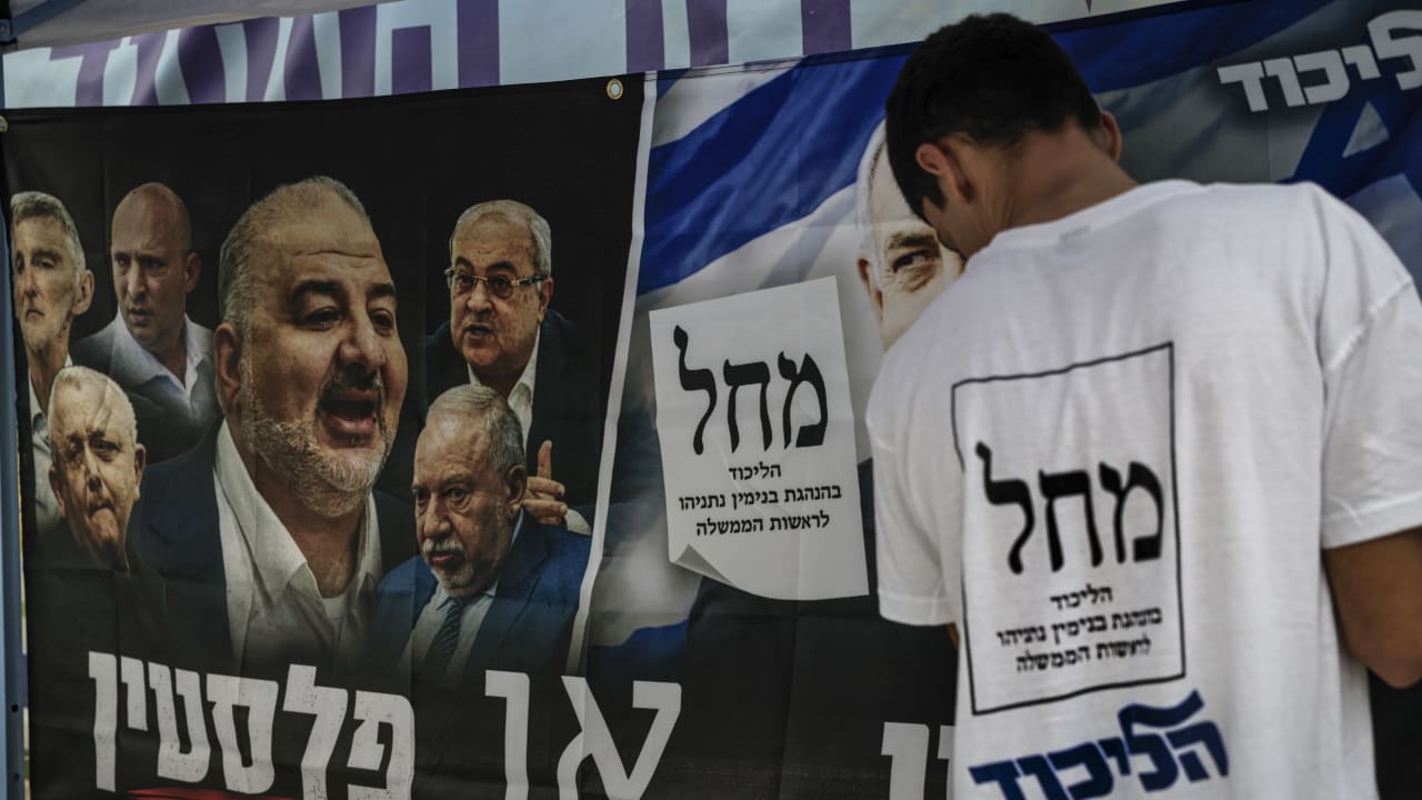 Political party activists gather near election campaign posters outside a polling station in the southern Israeli city of Ashkelon during Israel’s general elections, October 27, 2026.