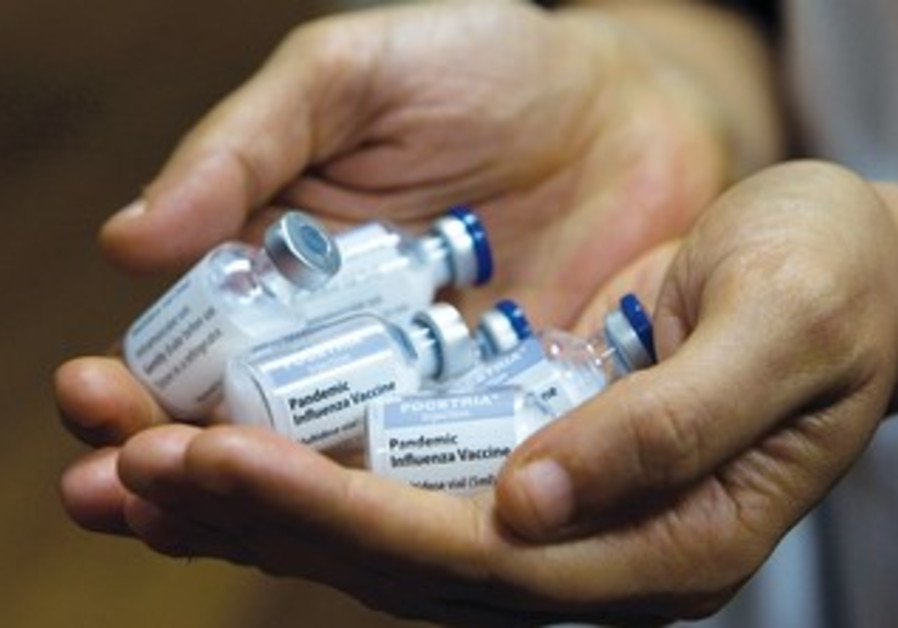 A medical worker holds vials containing the flu vaccine in Tel Aviv.