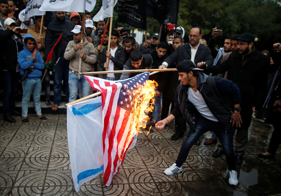 Palestinians burn signs depicting Israeli and American flags following President Trump's announcement about the US embassy move and recognition of Jerusalem as Israel's capital (credit: Mohammed Salem/ Reuters)