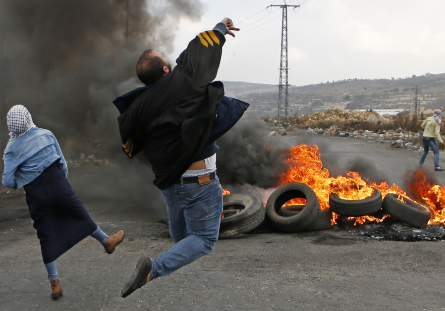 Palestinians throw stones at Israeli soldiers during a riot near Ramallah, December 2017 (credit: Abbas Momani/ AFP)
