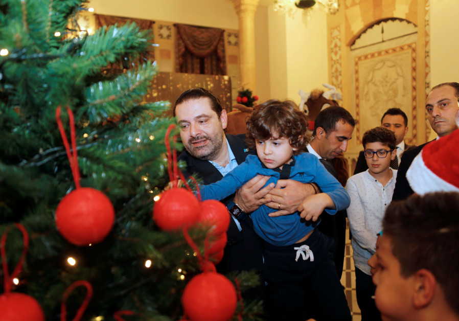 Prime Minister Saad Hariri helps a Lebanse orphan put an ornament on a Chrismtas tree (credit: Mohamad Azakir/ Reuters)