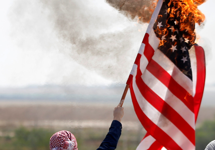 A Palestinian burns an American flag during protests in Gaza (credit: Mohammed Salem/ Reuters)