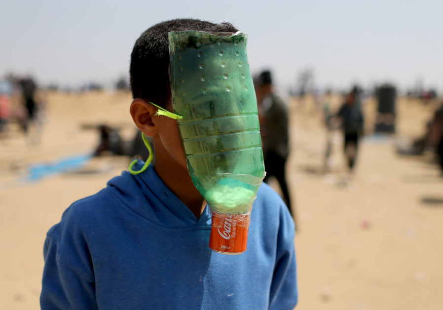 A Palestinian boy protects himself from tear gas during protests (credit: Ibraheem Abu Mustafa/ Reuters)