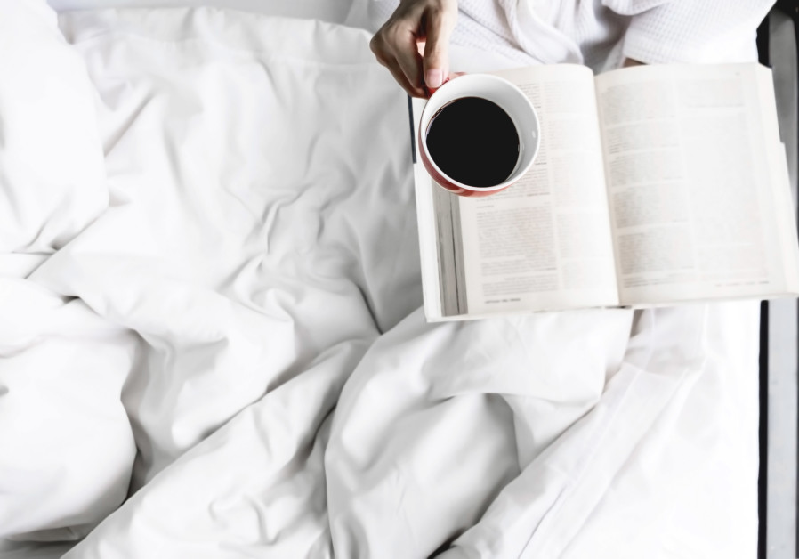 Photo of woman on the bed with old book and cup of coffee (INGIMAGE)