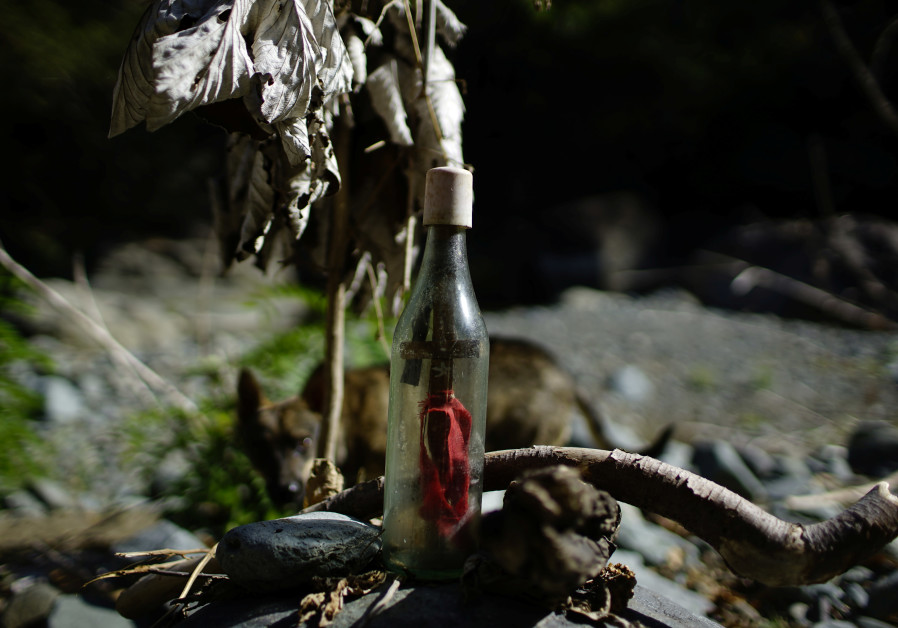 A bottle with a cross inside it, left by Santeria followers, is seen in the mountains near Santo Domingo, Cuba