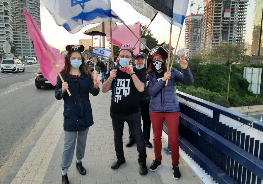 Protesters with pink flag and Purim costumes in Tel Aviv/ Courtesy 