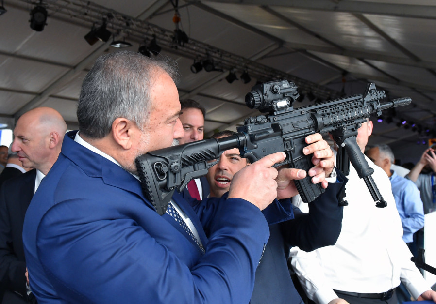 Defense Minister Avigdor Liberman holds a weapon during a visit to Sderot