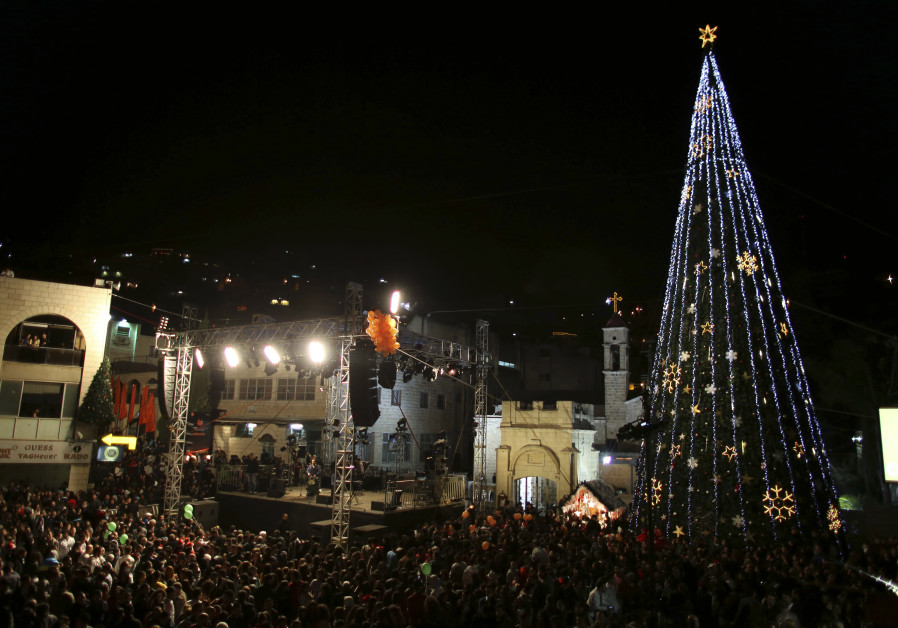 People attend a Christmas tree lighting ceremony in Nazareth (AMMAR AWAD/REUTERS)