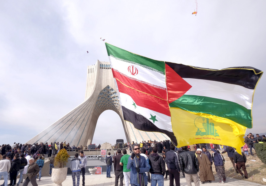 A man carries a giant flag made of flags of Iran, Palestine, Syria and Hezbollah, during a ceremony 