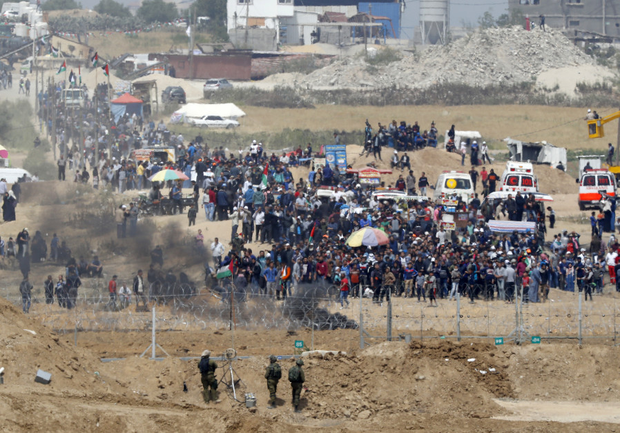 Israeli soldiers keeping position and Palestinian protestors gathering along the border fence