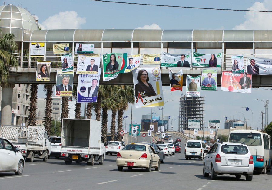 Vehicles drive under campaign posters ahead of the parliamentary election, in Erbil, Iraq