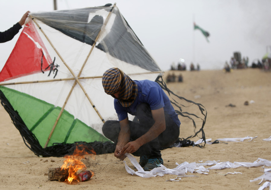 Palestinians prepare an incendiary device attached to a kite before trying to fly it over the border