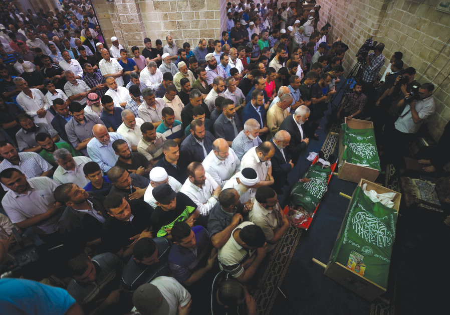 PALESTINIANS PRAY yesterday next to the bodies of Hamas terrorists killed by Israeli tank fire, duri