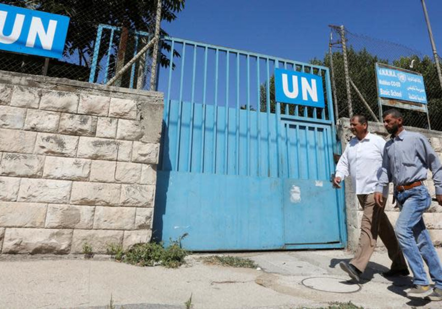 Palestinians pass by the gate of an UNRWA-run school in Nablus in the West Bank August 13, 2018