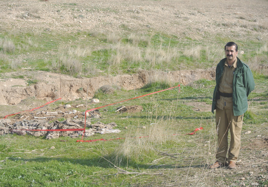 A Yazidi man stands next to a mass grave discovered in November 2015 after Kurdish forces liberated 