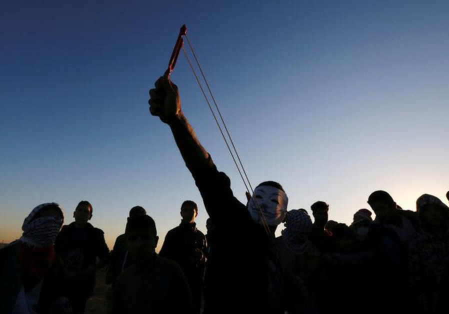 A Palestinian demonstrator uses a slingshot to hurl stones at Israeli troops.