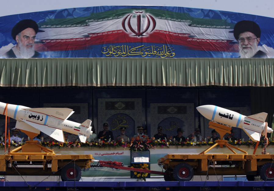 A military vehicle carrying Iranian Zoobin smart bomb (L) and Sagheb missile under pictures of Iran'