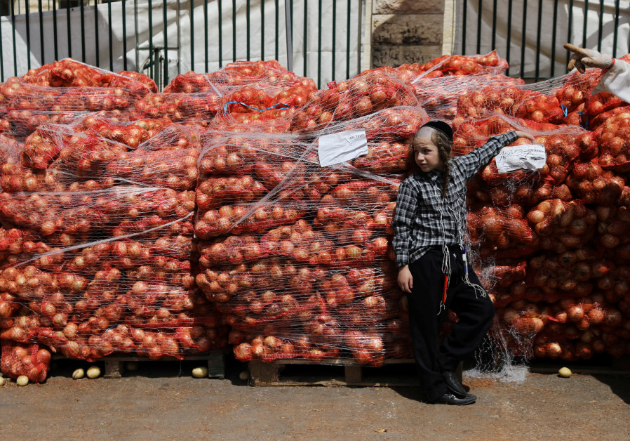 An ultra-Orthodox Jewish boy leans against sacks of onions at a food distribution center