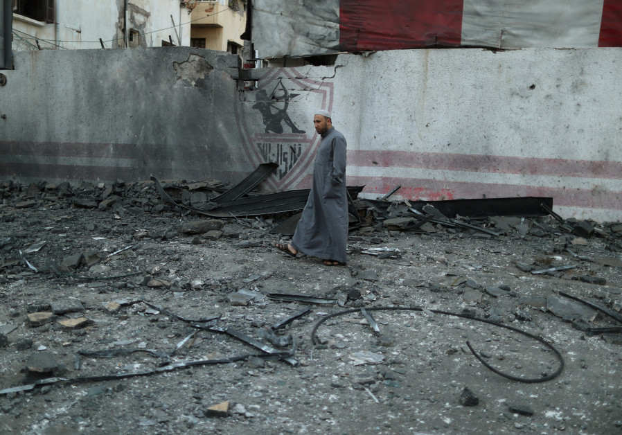 A Palestinian man walks through debris strewn from a building destroyed by Israeli air strikes, in G