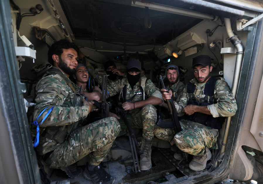 Turkey-backed Syrian rebel fighters sit inside a military vehicle near the border town of Tel Abyad,