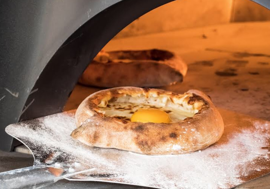 GET IT while it’s hot: Adjarian khachapuri, boat-shaped with cheese, butter and egg yolk in the middle. (Credit: Wikimedia Commons)