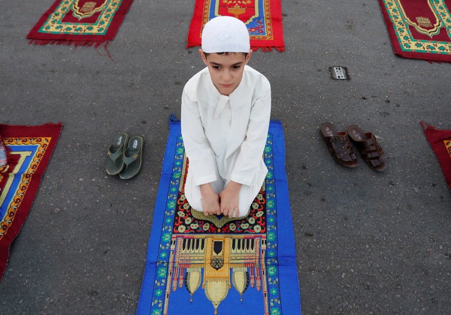 A boy attends Eid al-Adha prayers on the street outside Abu Hanifa mosque in Baghdad Adhamiya district, during the outbreak of the coronavirus disease (COVID-19), in Iraq, July 31, 2020. (Credit: REUTERS/Thaier Al-Sudani)