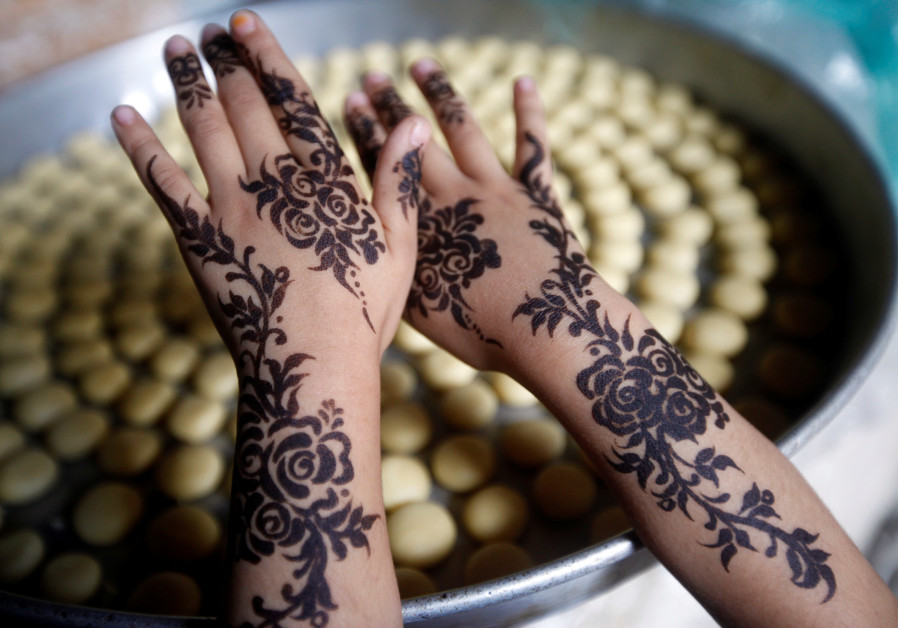 A girl displays a henna pattern applied on her hands for the Eid al-Adha festival at the old quarter of Sanaa, Yemen, July 30, 2020. (Credit: REUTERS/Mohamed al-Sayaghi)