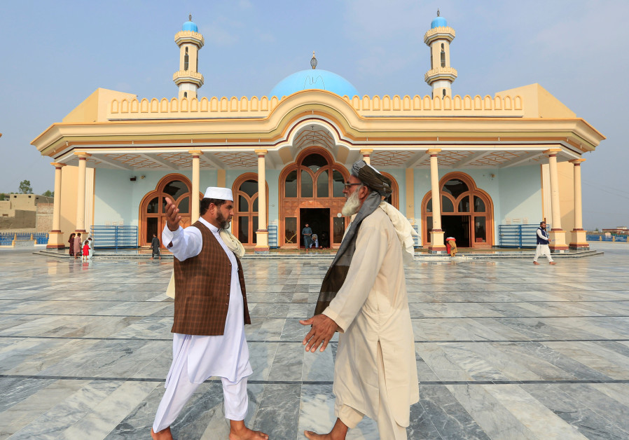 Afghan men greet each other outside a mosque after prayers during the Muslim festival of Eid al-Adha, amid the spread of the coronavirus disease (COVID-19), in Jalalabad, Afghanistan July 31, 2020. (Credit: REUTERS/Parwiz)