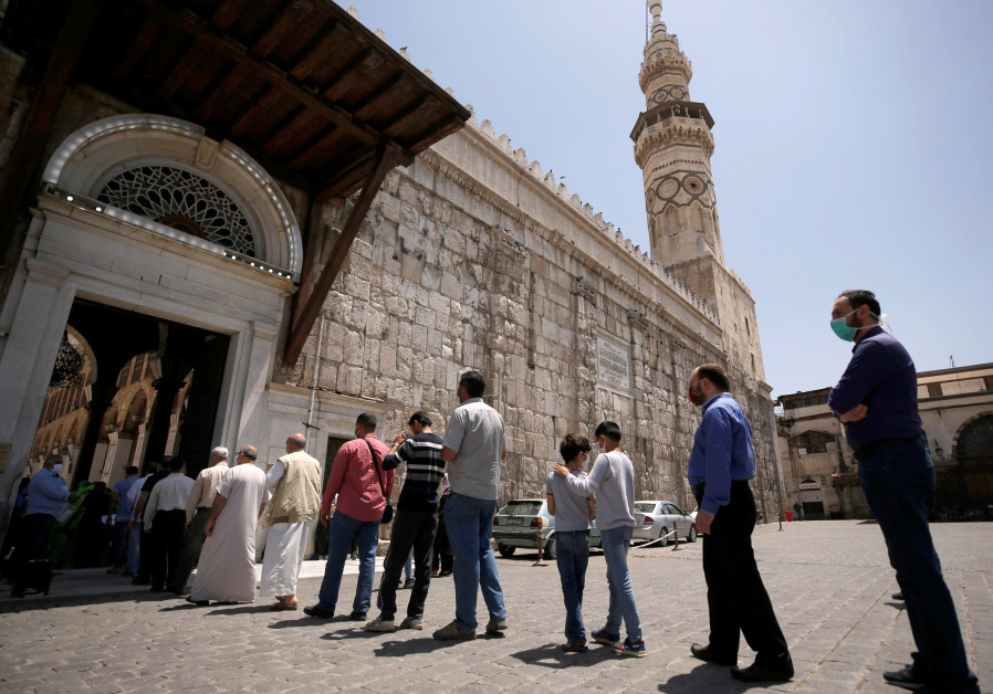 People wear face masks as they wait in line to enter and attend the Friday prayers, after the government has eased the restrictions amid concerns over the coronavirus disease (COVID-19) outbreak, at Umayyad mosque in Damascus, Syria May 8, 2020. (Credit: REUTERS/OMAR SANADIKI)