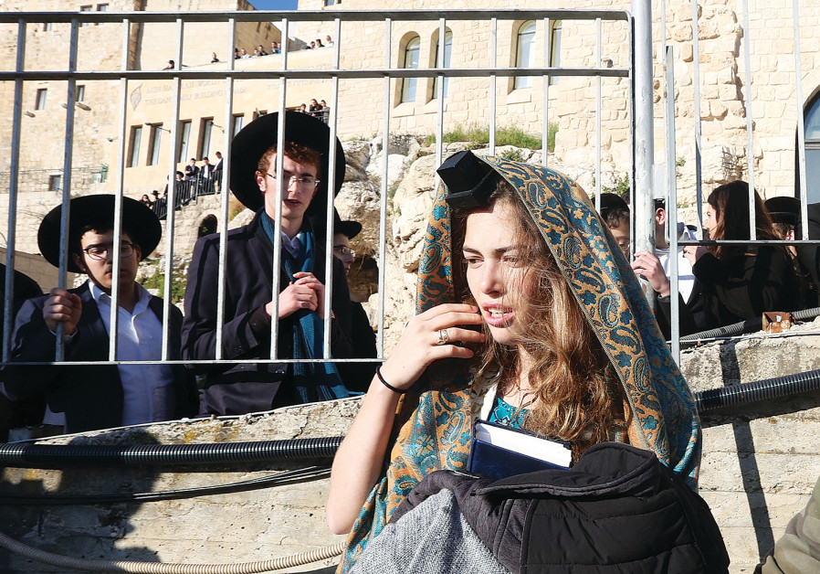 YOUNG HAREDIM look at a female worshiper with tefillin.