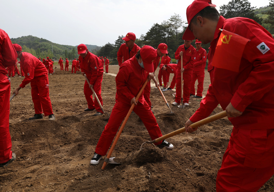 Party members from a company participate in a team-building event as they sow pumpkins near a former academy of China's Communist Party at Nanniwan, ahead of the 100th founding anniversary of the Communist Party of China, during a government-organised tour in Yanan, Shaanxi province, China, May 11, 2021. (REUTERS/Tingshu Wang)