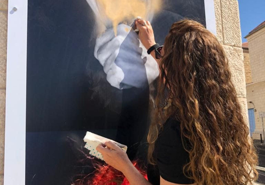 Peggy's niece scrubbing graffiti from the photo of Peggy Parner. (Credit: RINA CASTELNUOVO)