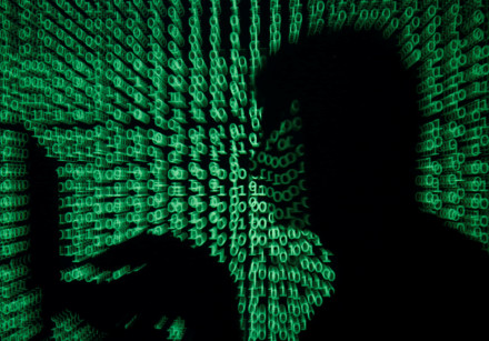 A man holds a laptop computer as cyber code is projected on him