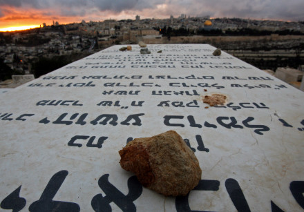 Stones placed in remembrance lie on grave tablets on the Mount of Olives Jewish cemetary as the sun sets in Jerusalem