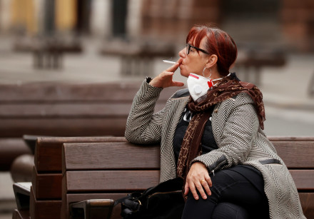 A woman smokes a cigarette as she sits on a bench in Liverpool